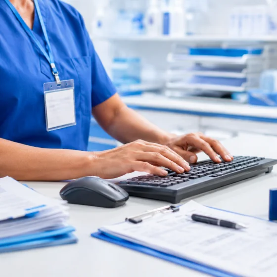 A clinician entering patient information at a workstation keyboard